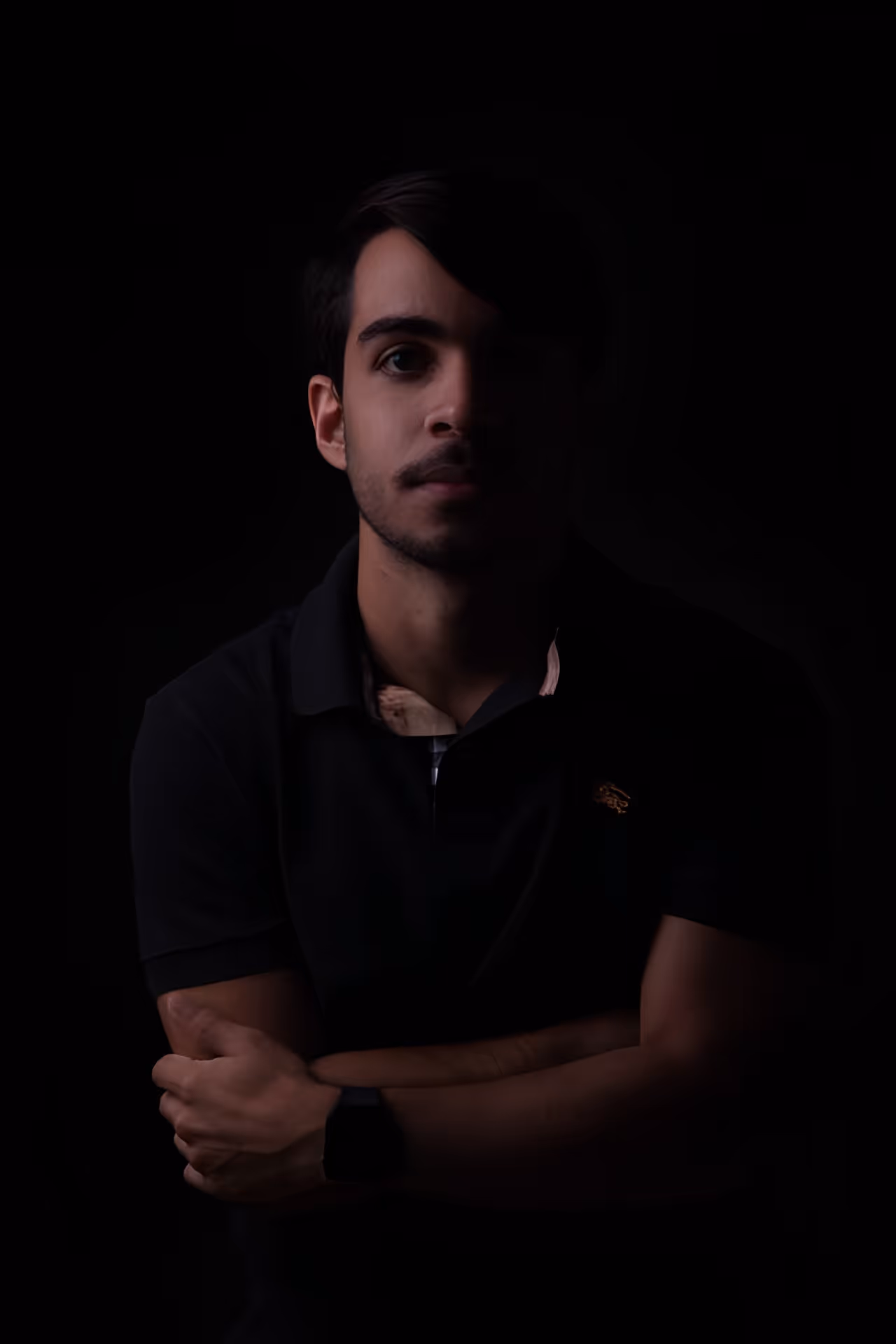 Portrait of João Victor in low light, arms crossed